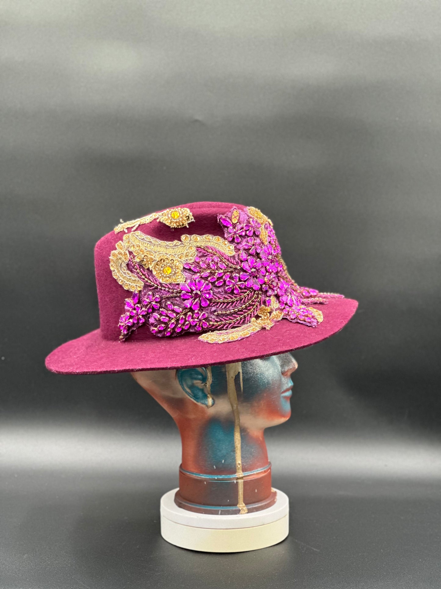 Close-up of the gold accents on the O'porto Magenta Wool Fedora Hat, highlighting the luxurious details, displayed on a mannequin head.
