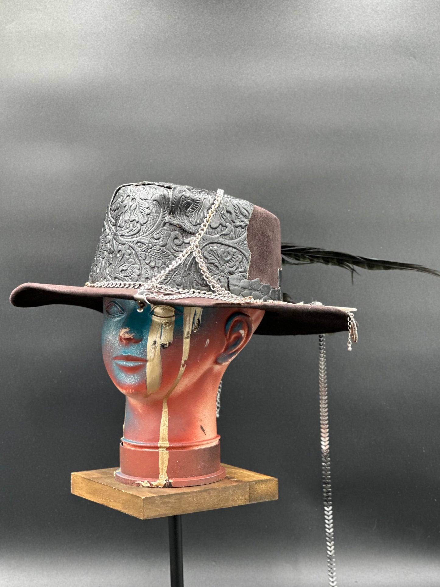 Angled view of the Algarve Black Cordobés Suede Hat, displaying the texture of the suede and the placement of the carved leather and chains