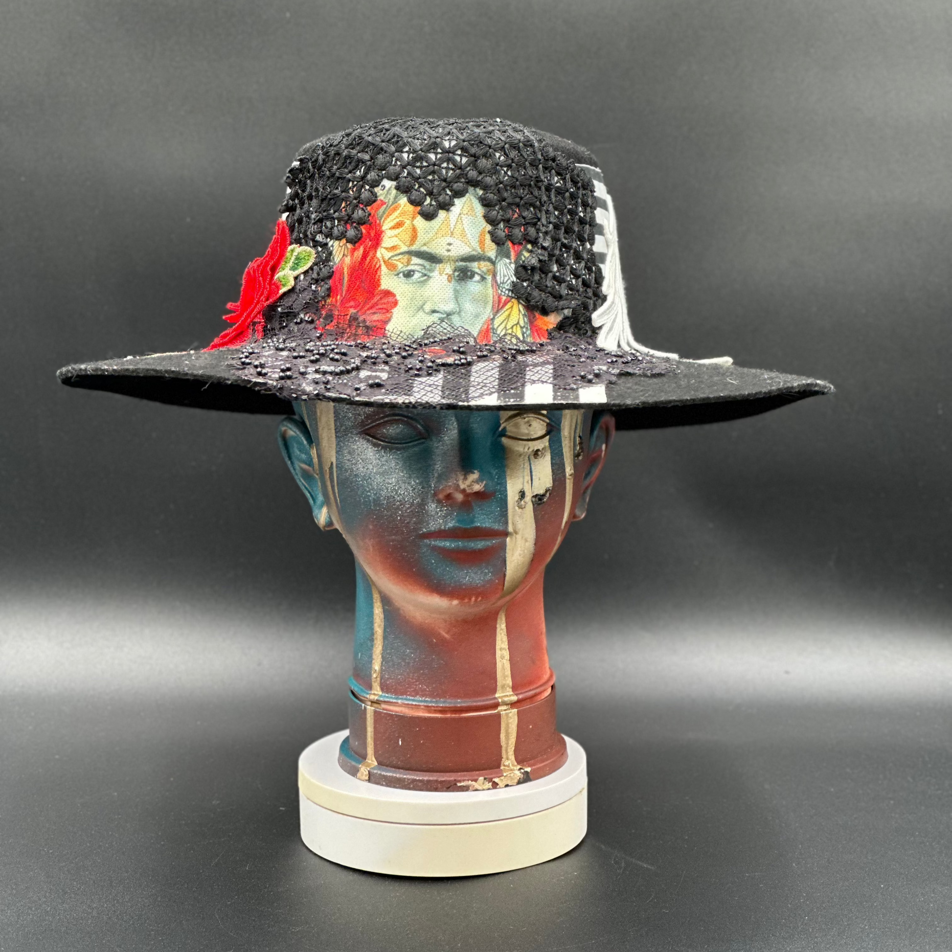 Coyoacán Frida Kahlo Black Wool Cordobés Hat with a collage of Frida Kahlo's image, lace, crochet, and red roses displayed on a mannequin head. Front view showing the hat's full design and shape.