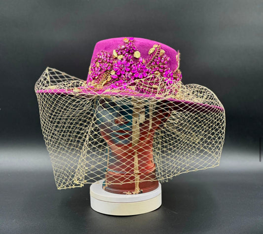 France Magenta Cordobés Wool Hat with a gold veil and crystal centerpiece displayed on a mannequin head. Front view showing the hat's full design and shape.