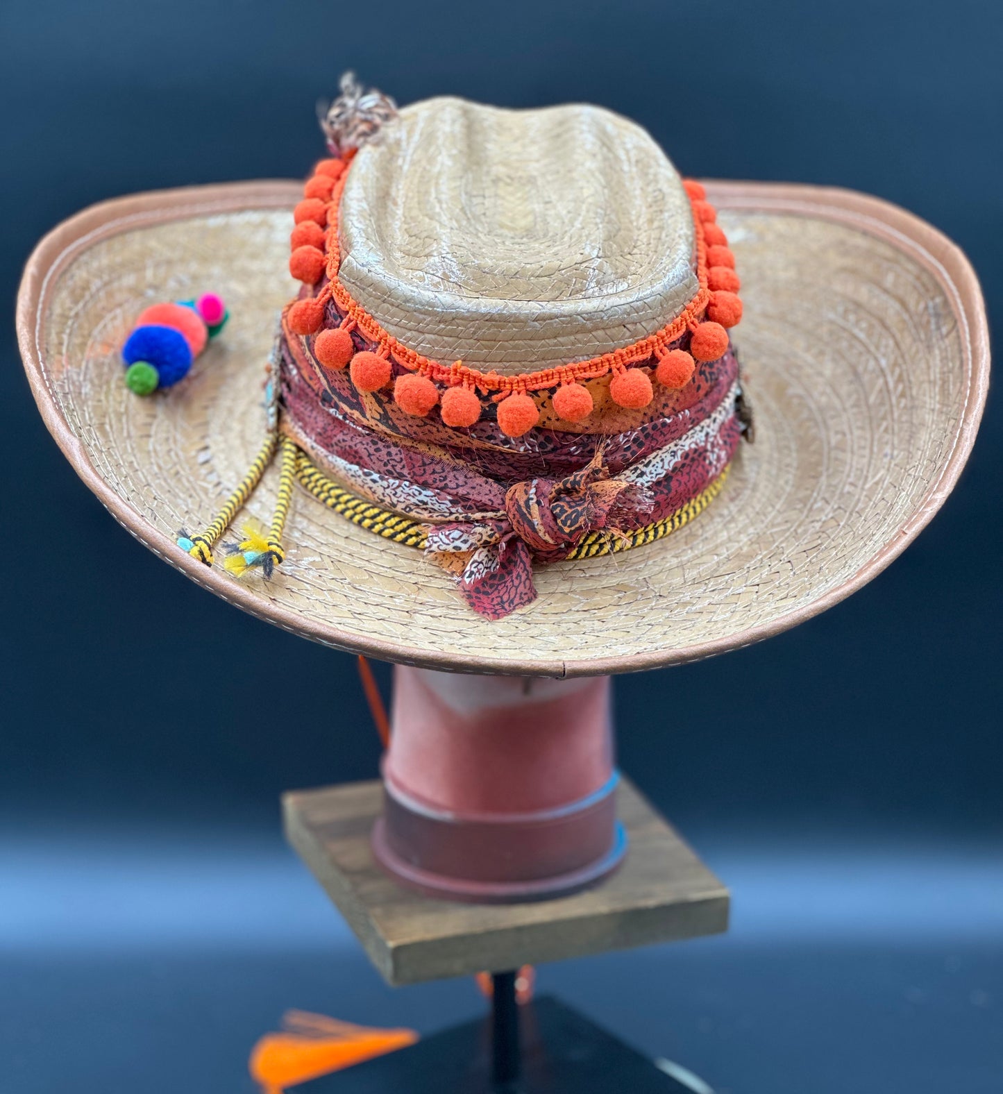 Close-up of the Colombia Straw Hat showcasing the intricate beadwork, orange pom-poms, and unique bird design. Handmade artisanal details.