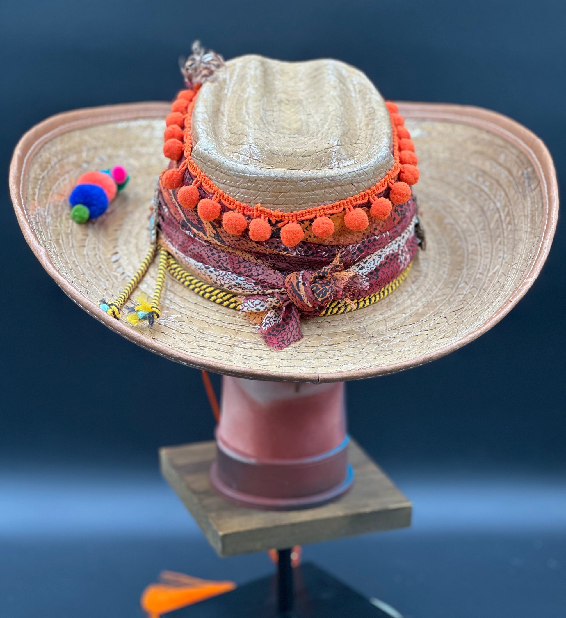 Close-up of the Colombia Straw Hat showcasing the intricate beadwork, orange pom-poms, and unique bird design. Handmade artisanal details.