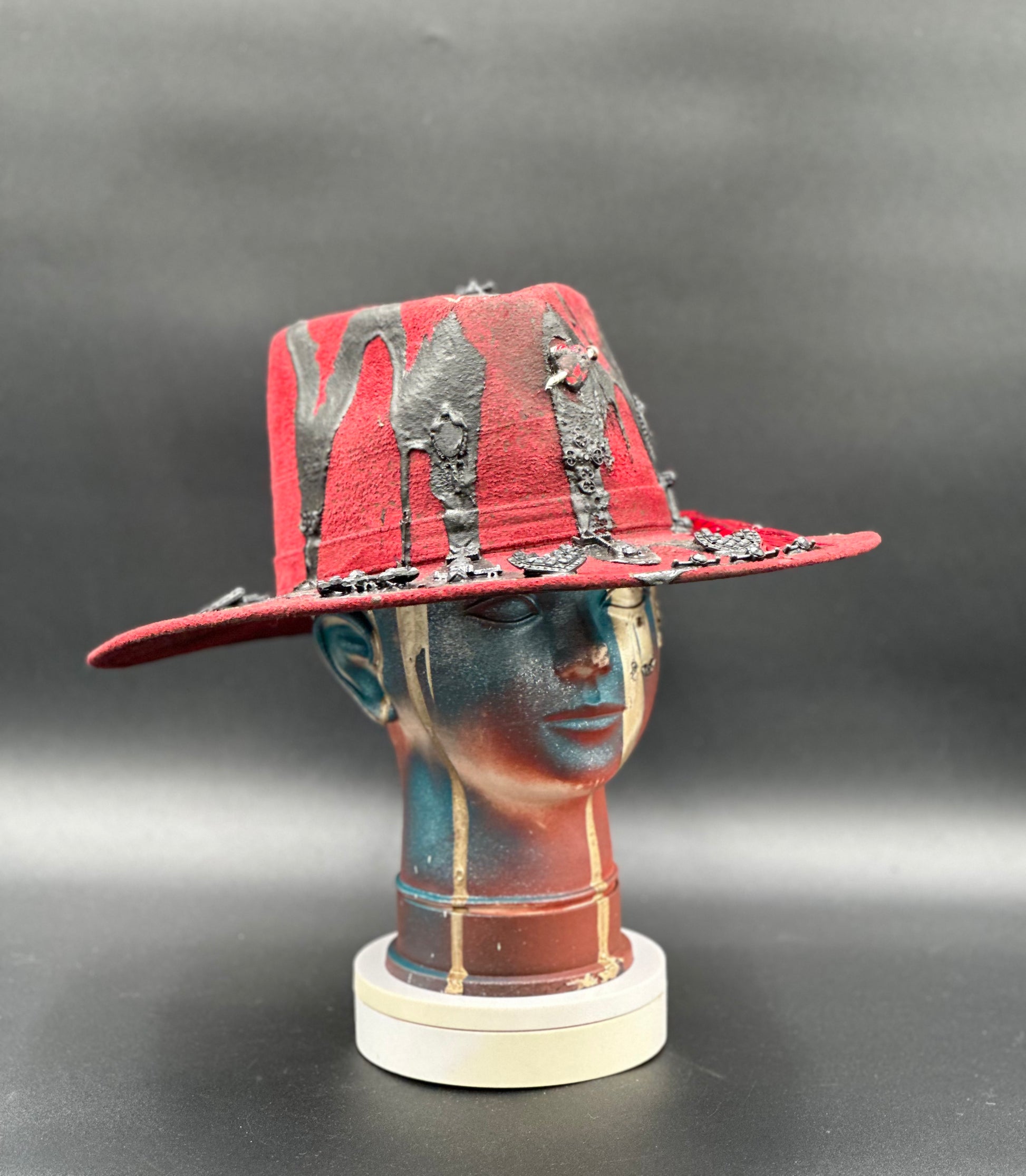 Angled view of the Madrid Red Arrow Suede Hat, displaying the texture of the suede and the placement of the lava drops and charms.