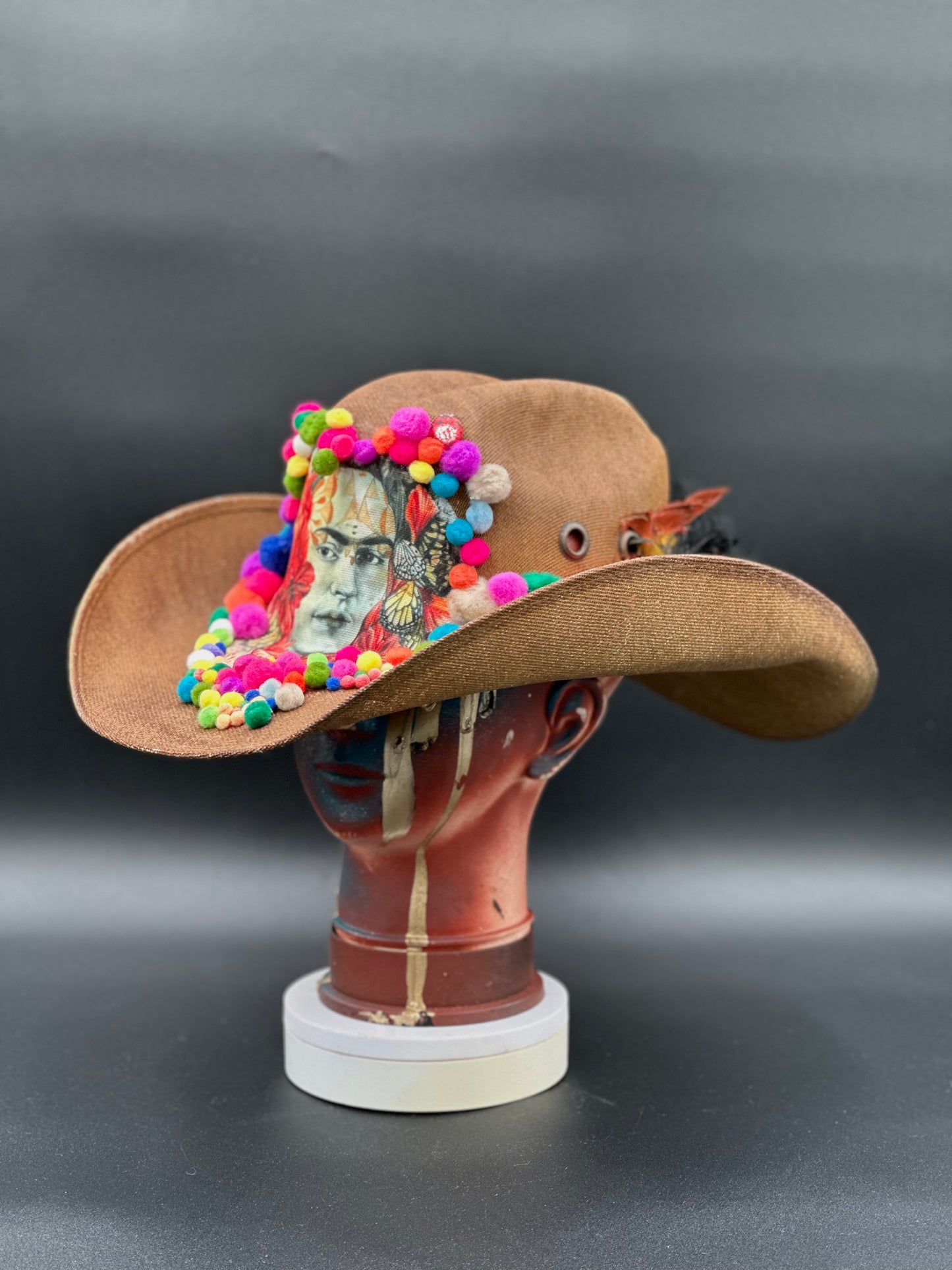 Frida in Cotton - Brown Straw Cowboy Hat on a mannequin head, showcasing the hat's festival-ready style and vibrant colors.