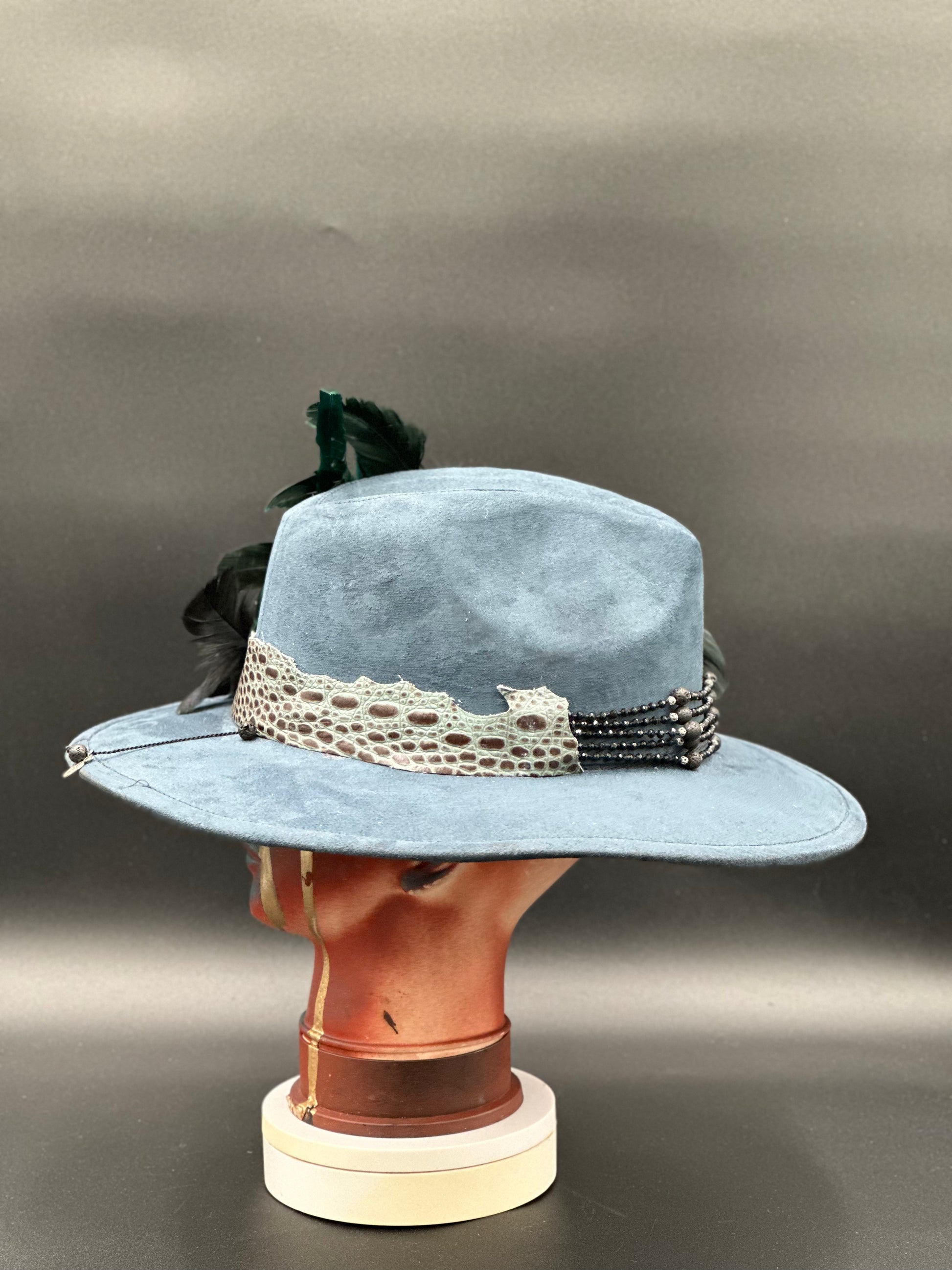 Lisboa Blue Suede Fedora Hat on a mannequin head, showcasing the hat's unique style and artistic flair.