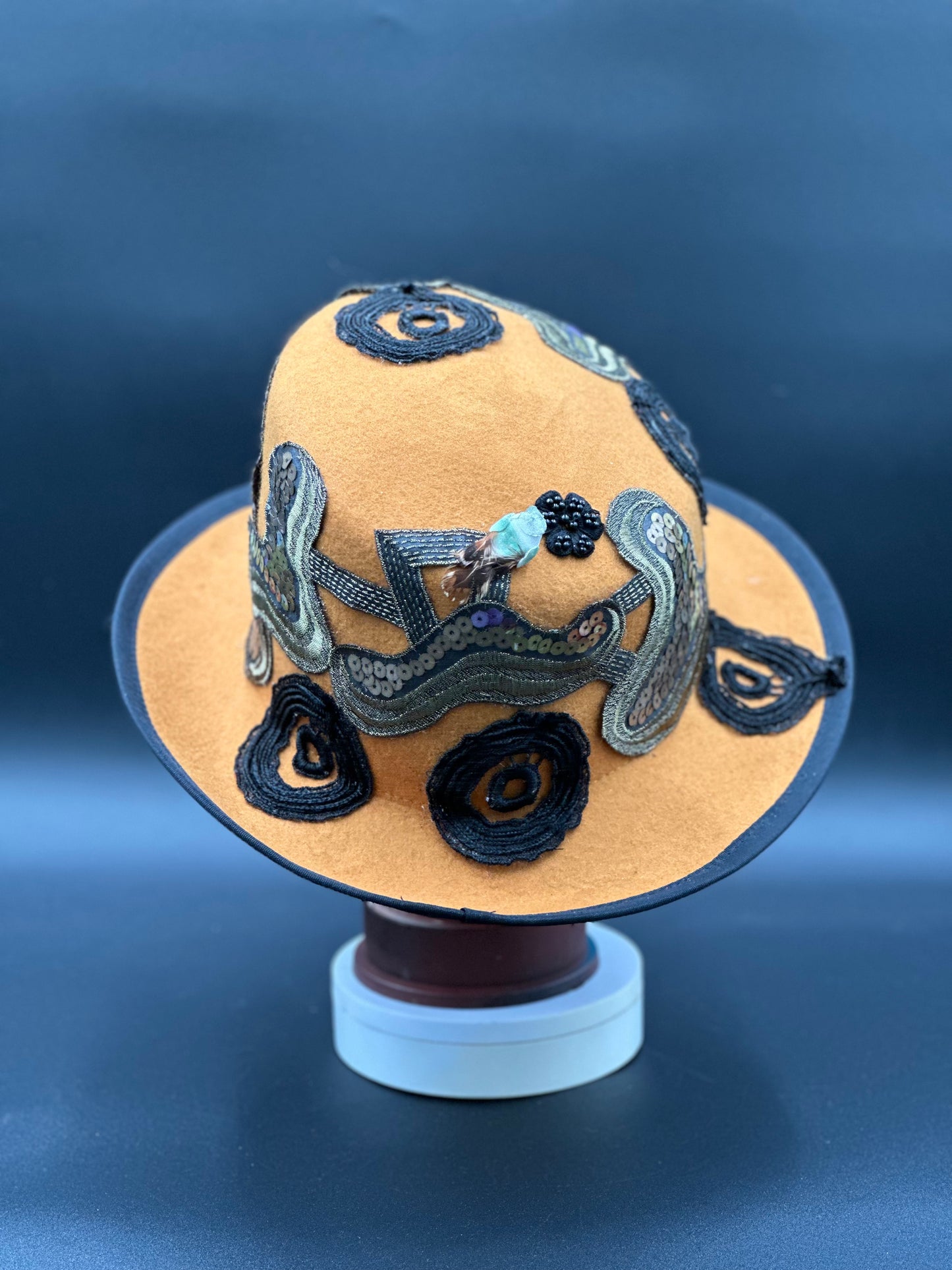 Side view of the New Orleans Mustard Wool Top Hat, highlighting the unique fabric patterns and the hat's shape.