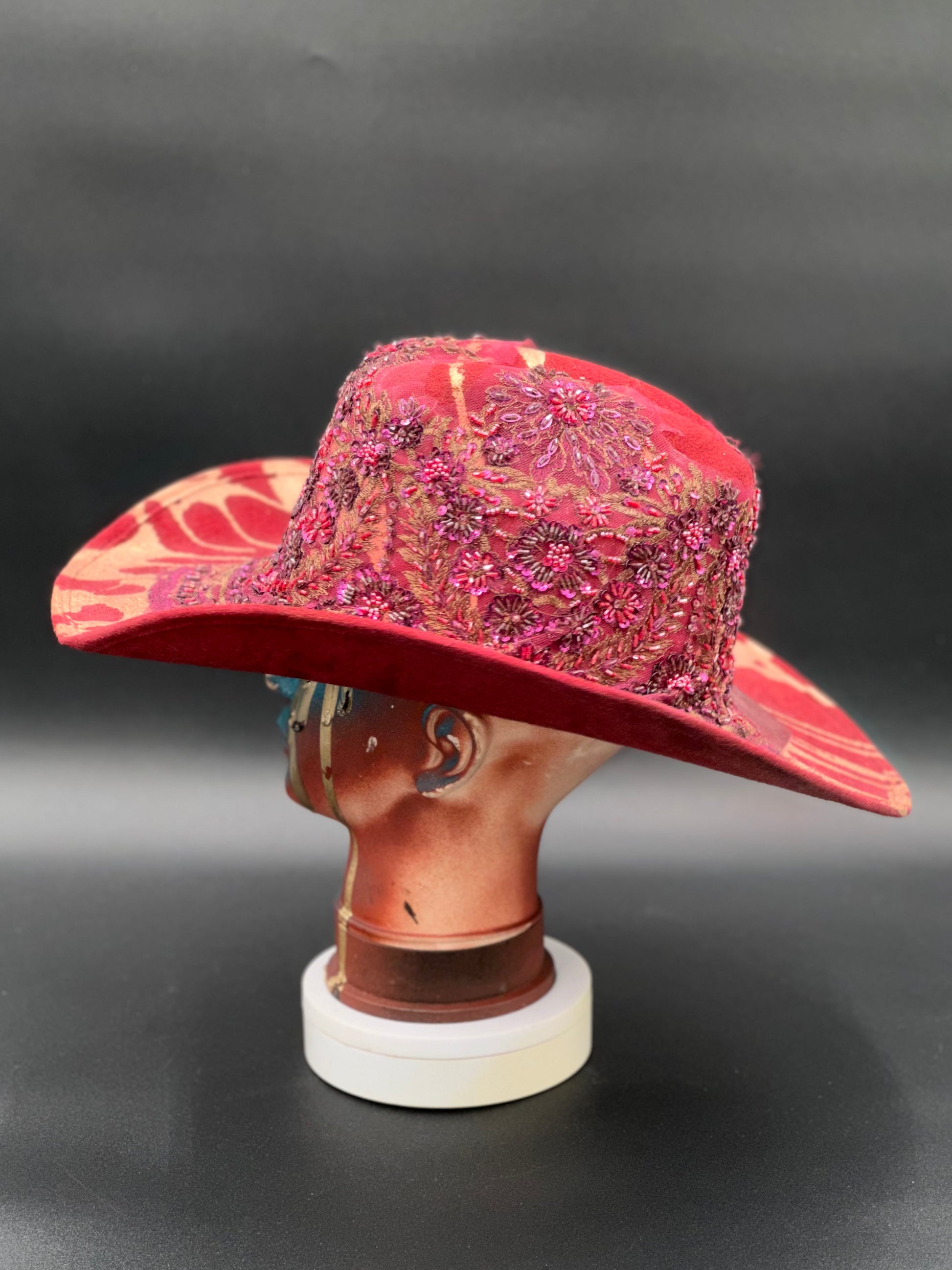 Side view of the North Miami Red Suede Hat on a mannequin head, highlighting the crystal placement and the hat's silhouette.