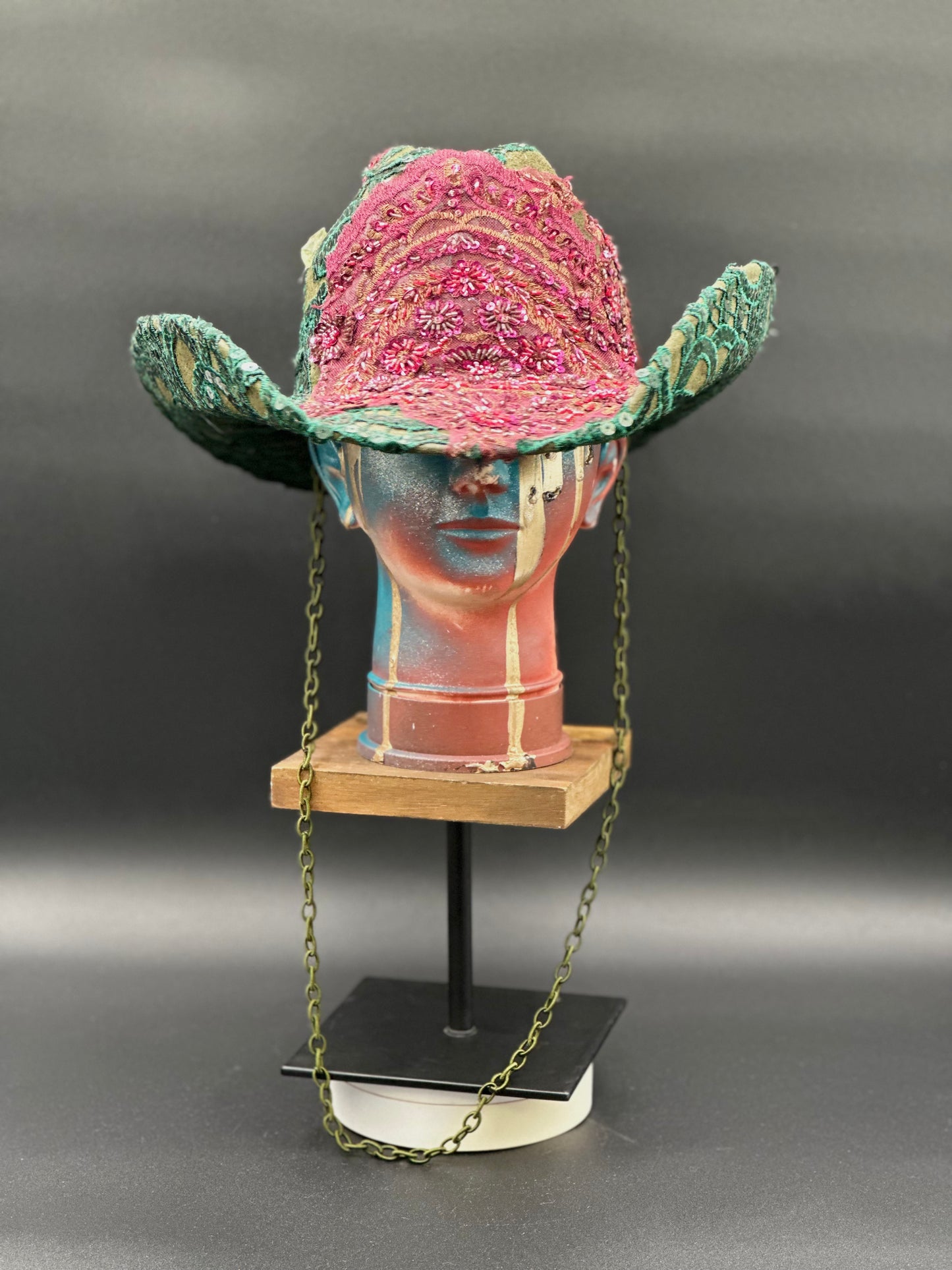 Close-up of the stoned burgundy lace centerpiece on the Deep Forest Green Suede Cowboy Hat, highlighting the intricate details, displayed on a mannequin head.