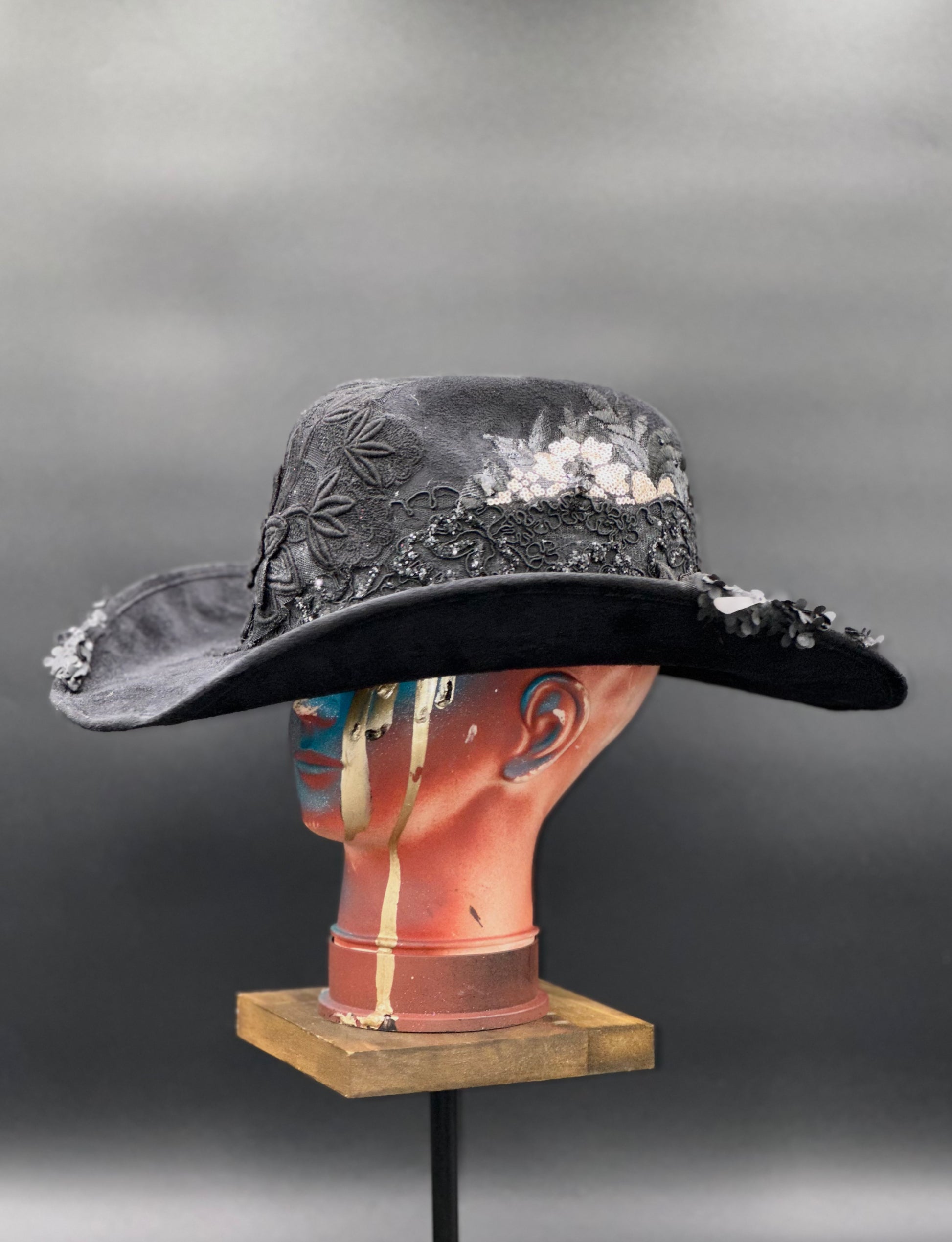 Angled view of the Zorro Black Suede Cowboy Hat on a mannequin head, displaying the texture of the mixed fabrics and the placement of the crochet centerpiece.