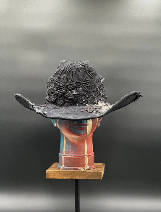 Zorro Black Suede Cowboy Hat with mixed fabrics, laces, and an embroidered crochet centerpiece displayed on a mannequin head. Front view showing the hat's full design and shape.