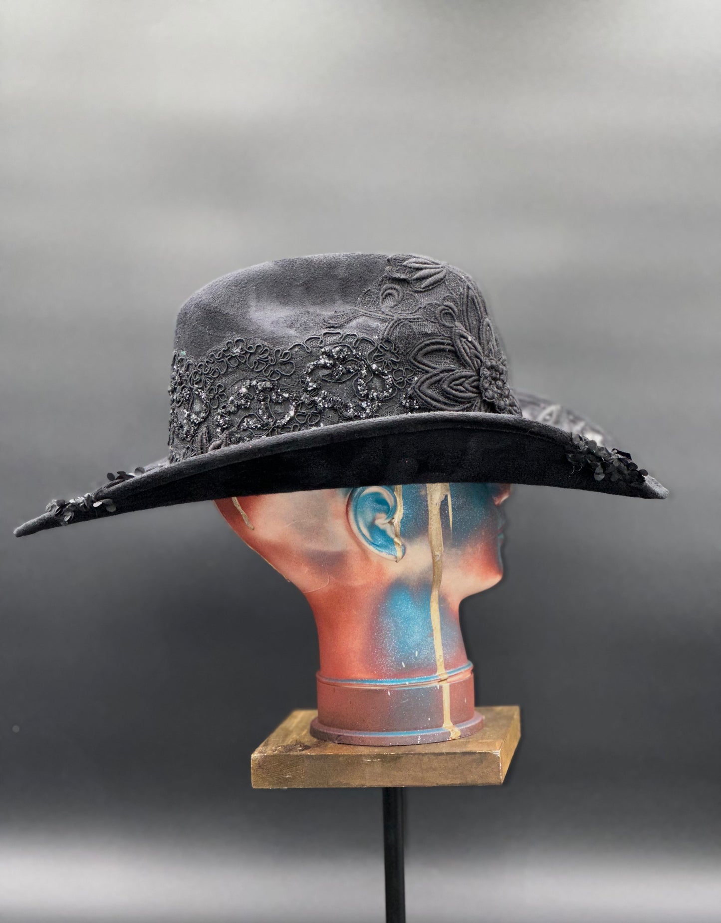 Side view of the Zorro Black Suede Cowboy Hat on a mannequin head, highlighting the crochet centerpiece placement and the hat's silhouette.
