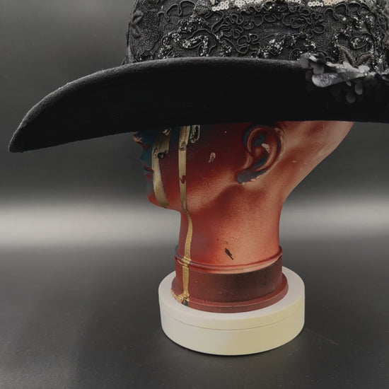 360-degree video of the Zorro Black Suede Cowboy Hat rotating on a mannequin head, showcasing the hat's full design, mixed fabrics, laces, and embroidered crochet centerpiece from all angles.