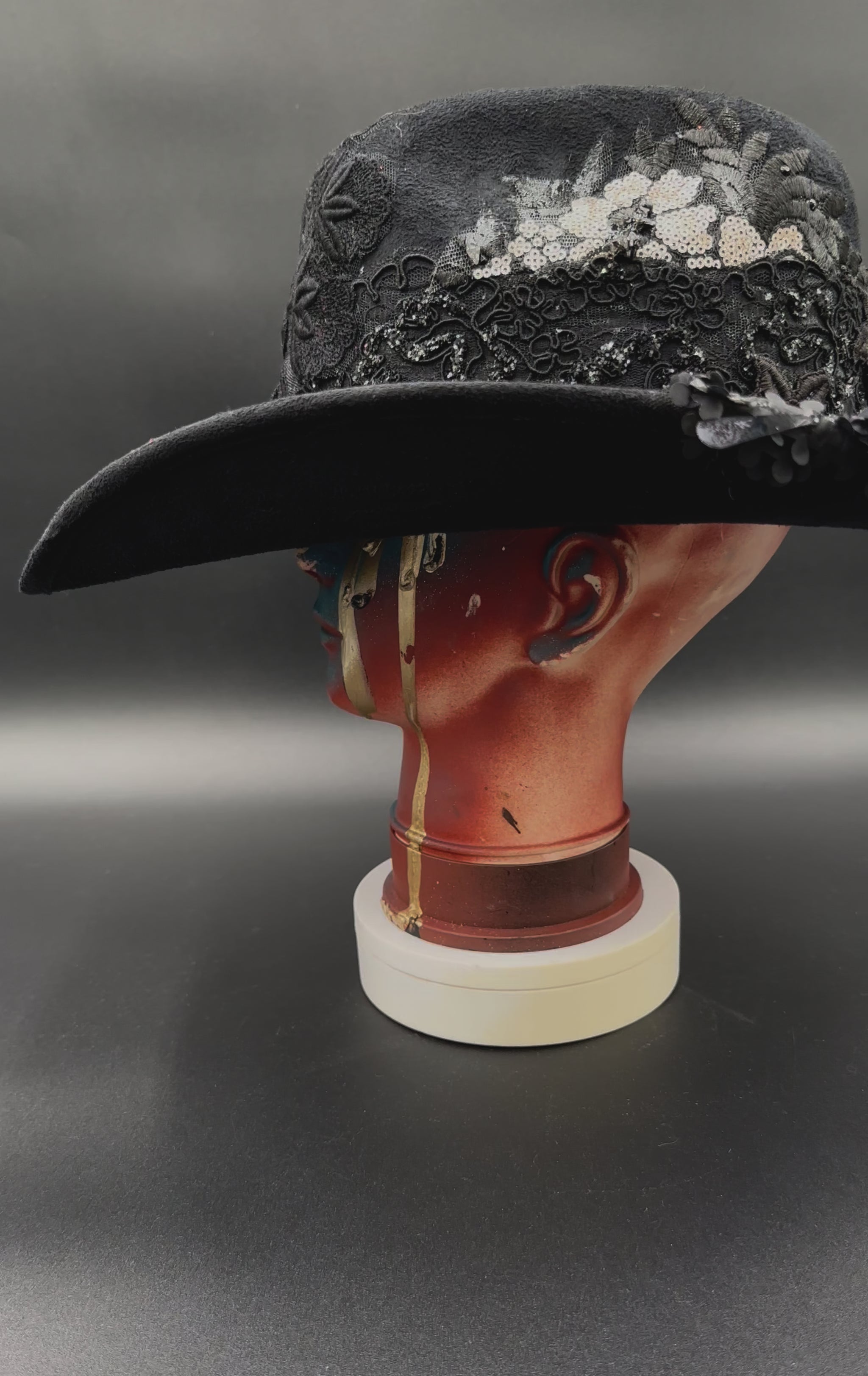 360-degree video of the Zorro Black Suede Cowboy Hat rotating on a mannequin head, showcasing the hat's full design, mixed fabrics, laces, and embroidered crochet centerpiece from all angles.