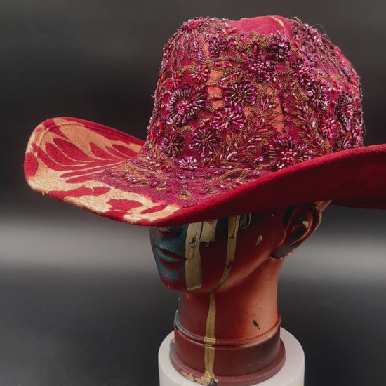 360-degree video of the North Miami Red Suede Hat rotating on a mannequin head, showcasing the hat's full design, red suede texture, gold splash, and crystal centerpiece from all angles.