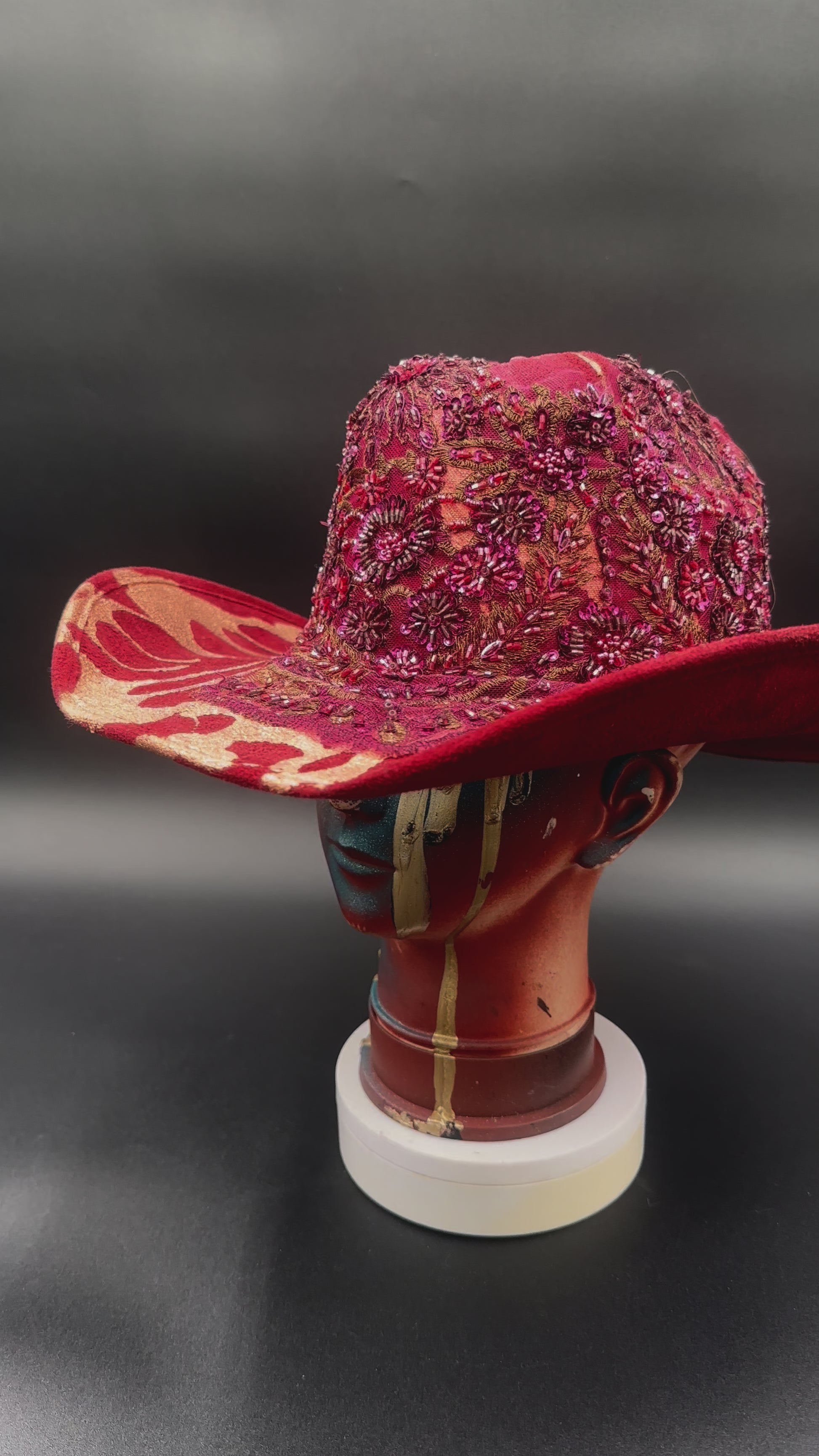 360-degree video of the North Miami Red Suede Hat rotating on a mannequin head, showcasing the hat's full design, red suede texture, gold splash, and crystal centerpiece from all angles.